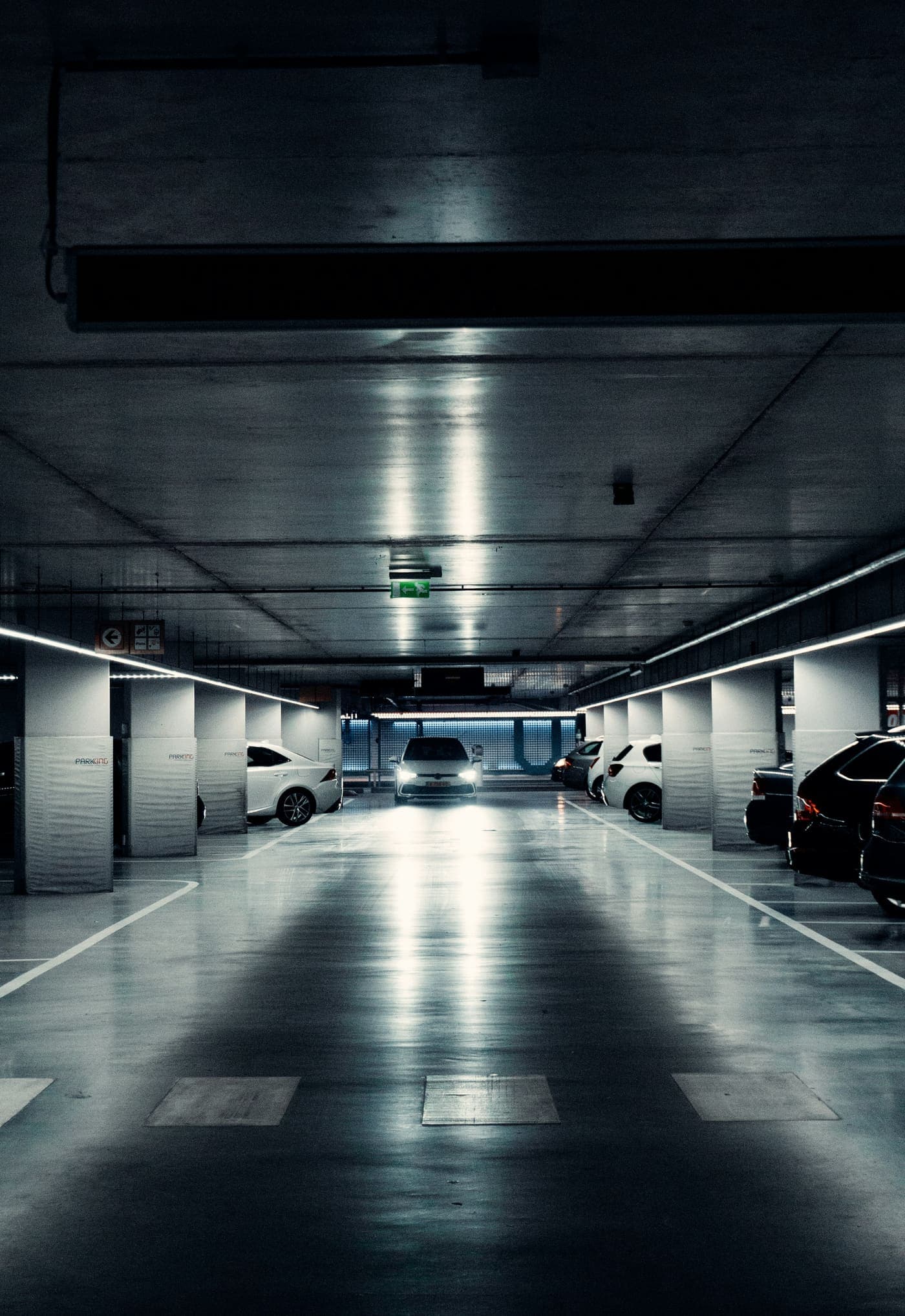 Sótano de parqueadero iluminado, con un carro entrando al fondo